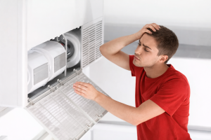 Homeowner inspecting indoor air conditioning unit with open panel